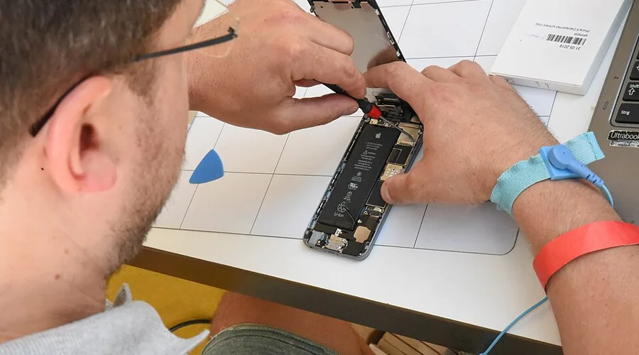 Technician working on the internal components of an opened smartphone